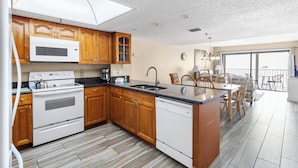 A modern kitchen with wooden cabinets, a built-in microwave, and a dishwasher. - Direct Beachfront 3B2B Gulf - Beach Place #408 (Madeira Beach)