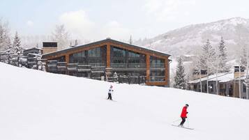 Un centro de esquí con un edificio moderno, pistas de nieve y árboles cubiertos de nieve.