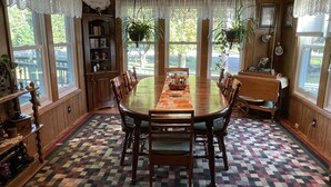 Une salle à manger avec une grande table en bois, des chaises, un lustre et un tapis à motifs.