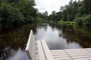 Um cais de madeira que se estende por um rio calmo, rodeado por vegetação densa.