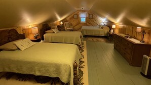 Une chambre mansardée chaleureuse, avec deux lits, une commode et une petite fenêtre.