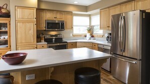 Une cuisine moderne avec des meubles en bois, des appareils en acier inoxydable et un grand îlot central.
