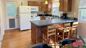 A kitchen with wooden cabinets, a white refrigerator, a stove, and a sink. There are two hanging lights and a window with blinds. - Bedrooms 4, Bathrooms 2, Sleeps 8 (Linden)