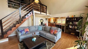A spacious living room with a large gray sectional sofa, a wooden coffee table, and a staircase leading to an upper level. - Bedrooms 4, Bathrooms 2, Sleeps 8 (Linden)