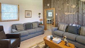 A living room with two sofas, a coffee table, and a ceiling fan. - McNeal Cottage:  Comfortable home, large private back yard. (Ocracoke)