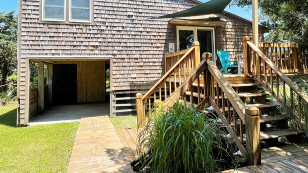 A wooden house with a covered porch, a wooden staircase, and a green chair. - McNeal Cottage:  Comfortable home, large private back yard. (Ocracoke)
