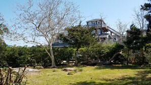 A large house with a prominent tower, surrounded by dense greenery and trees. - The Mary Francis: Dog friendly, near Springers Point and Lighthouse (Ocracoke)