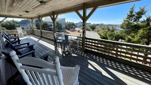 A covered outdoor seating area with wooden benches and tables, overlooking a road and buildings. - Harbor II: Pet friendly, views of both the Lighthouse and Silver Lake. (Ocracoke)