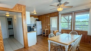A wooden interior with a dining table, chairs, a ceiling fan, and a kitchen area. - Harbor II: Pet friendly, views of both the Lighthouse and Silver Lake. (Ocracoke)