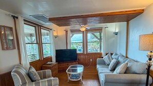 A living room with a sofa, armchair, TV, and a coffee table. - Harbor II: Pet friendly, views of both the Lighthouse and Silver Lake. (Ocracoke)