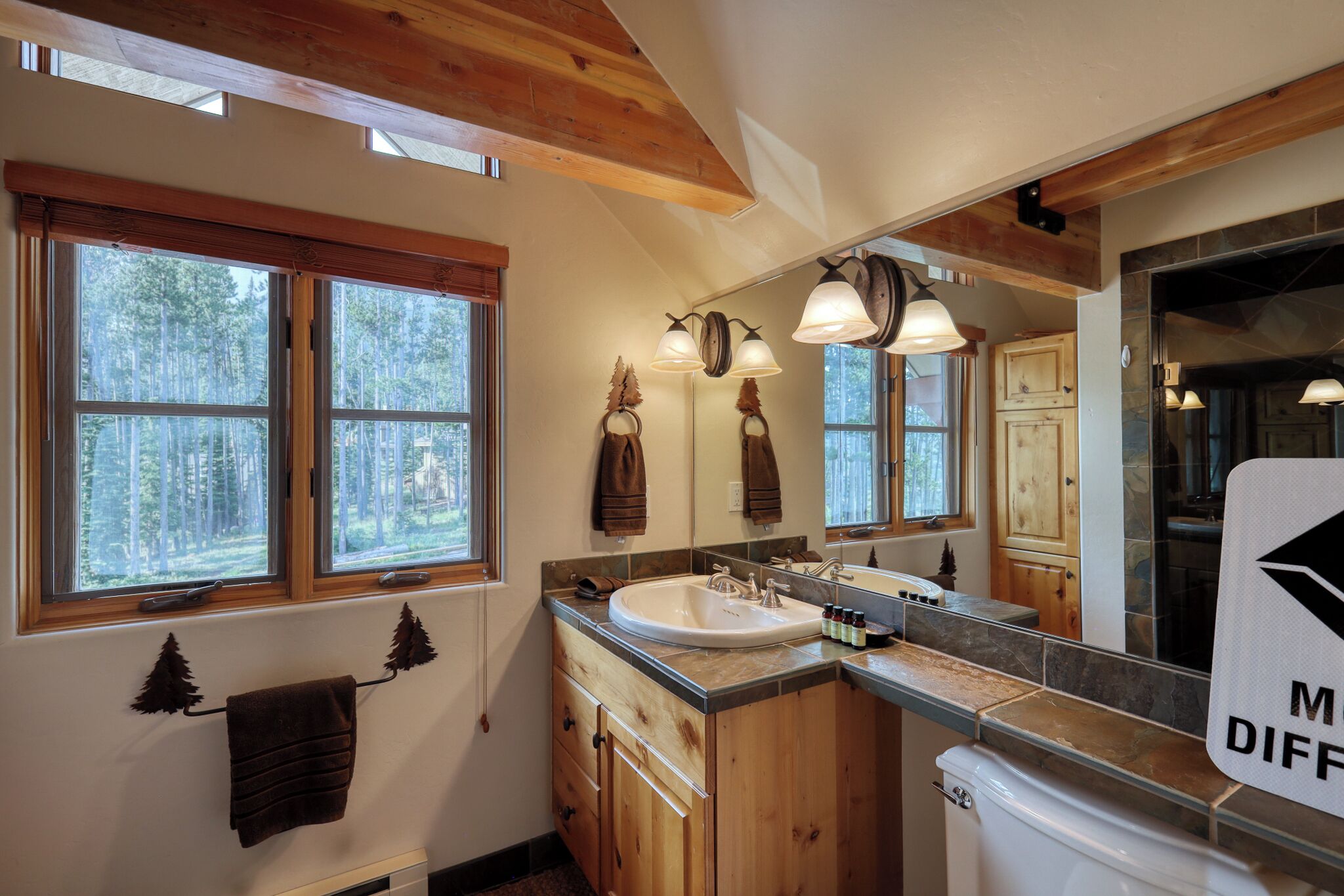 A bathroom with wooden cabinets, a large mirror, and a sink.