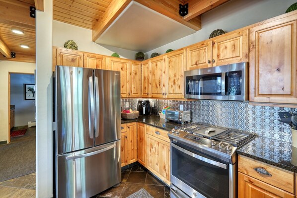 A modern kitchen with wooden cabinets, stainless steel appliances, and a patterned backsplash.