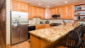 A kitchen with wooden cabinets, stainless steel appliances, a granite countertop, and a central island with chairs. - Spacious Park City 4BR, Walk to Three Kings Lift, Mountain Views, Pool  & Hot Tu (Park City)