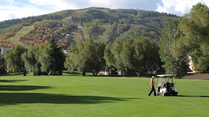 A golf course with a person walking and a golf cart. - Spacious Park City 4BR, Walk to Three Kings Lift, Mountain Views, Pool  & Hot Tu (Park City)
