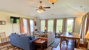 Un vaste espace de vie comprenant un canapé bleu, une table à manger en bois et un ventilateur de plafond.