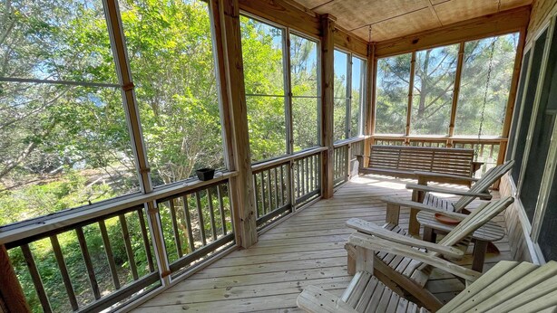 Une terrasse en bois offrant une vue sur les arbres, avec un banc.