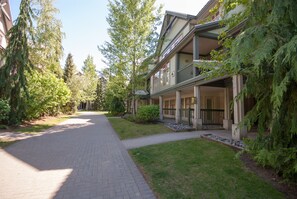 A pathway leading to a building with a covered porch and a garden area.