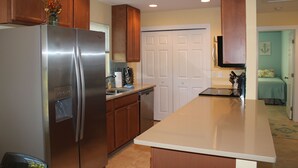 A kitchen with wooden cabinets, a stainless steel refrigerator, a dishwasher, and a white door.