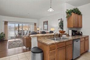 Una cocina con encimera de granito, pileta de acero inoxidable, muebles de madera y lavavajillas.