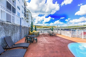 Zona de piscina en la azotea con mobiliario exterior y vistas al agua.