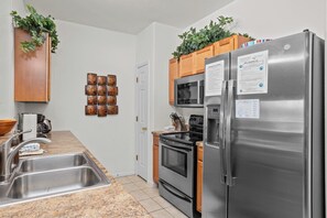 Una cocina moderna con electrodomésticos de acero inoxidable, encimeras de granito y armarios de madera.