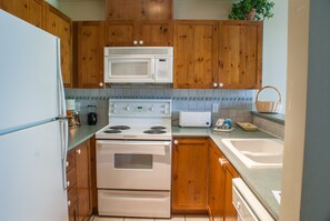 A kitchen with wooden cabinets, a white stove, a microwave, and a toaster.