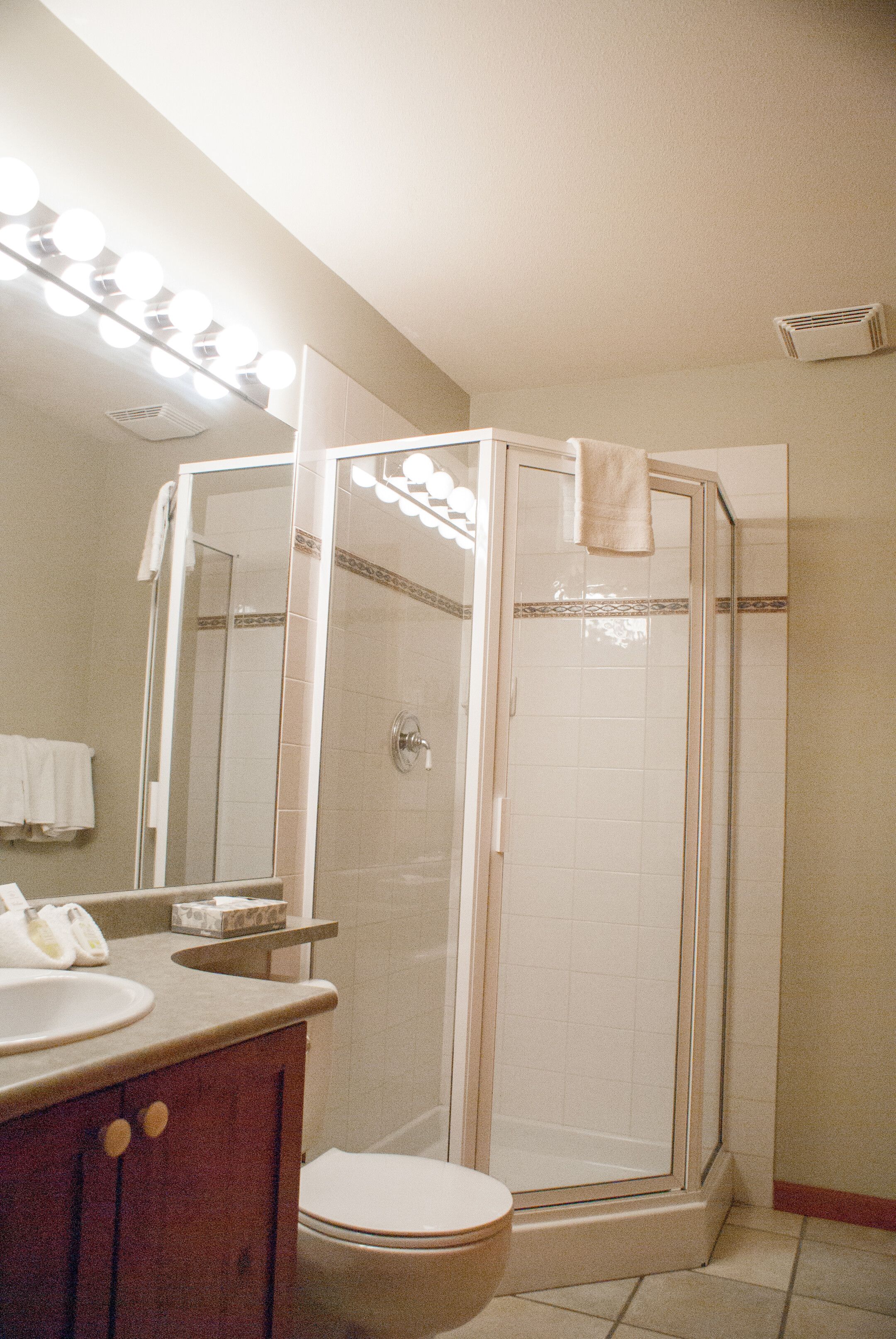 A bathroom with a shower, toilet, sink, and mirror.