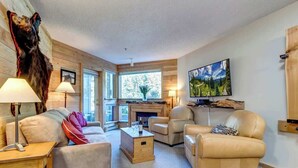 A cozy living room with a fireplace, leather sofas, and a mounted bear head.