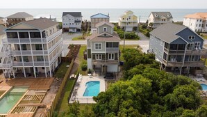 A coastal residential area with multiple two-story houses, a swimming pool, and a view of the ocean.