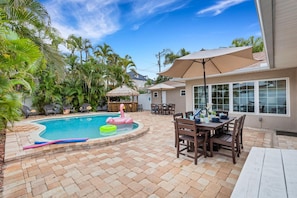 Ein Garten mit Swimmingpool, Terrassenmöbeln und Essbereich.