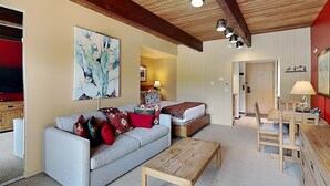 Una sala de estar con un sofá, una mesa de centro de madera, una zona de comedor con una mesa y sillas, y un cuadro en la pared.