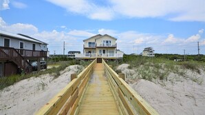 A wooden boardwalk leading to a beachfront house with a balcony and multiple windows. - Experience beachside bliss at Almost Heaven North, a spacious 4-bedroom duplex in North Topsail! (North Topsail Beach)