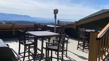 An outdoor patio with tables and chairs, a lamp post, and a view of mountains.