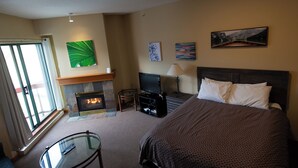 A hotel room with a bed, a television, a fireplace, and artwork on the walls. - Great Value Village Condo, Close to Everything, Hot Tub Access, Free Parking (Whistler)