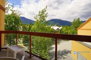 Ein Balkon mit Blick auf ein Gebirge, Bäume und ein Gebäude mit gelber Fassade.
