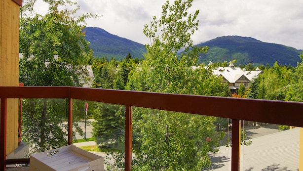 A balcony with a view of mountains, trees, and a building in the background. - Great Value Village Condo, Close to Everything, Hot Tub Access, Free Parking (Whistler)
