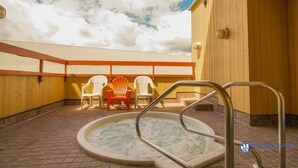 A hot tub area with a wooden deck, a pool ladder, and Adirondack chairs. - Great Value Village Condo, Close to Everything, Hot Tub Access, Free Parking (Whistler)