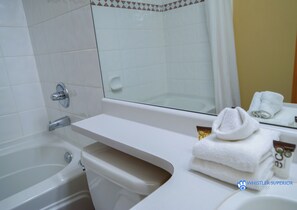 Bathroom features a bathtub, toilet, and sink with a mirror.