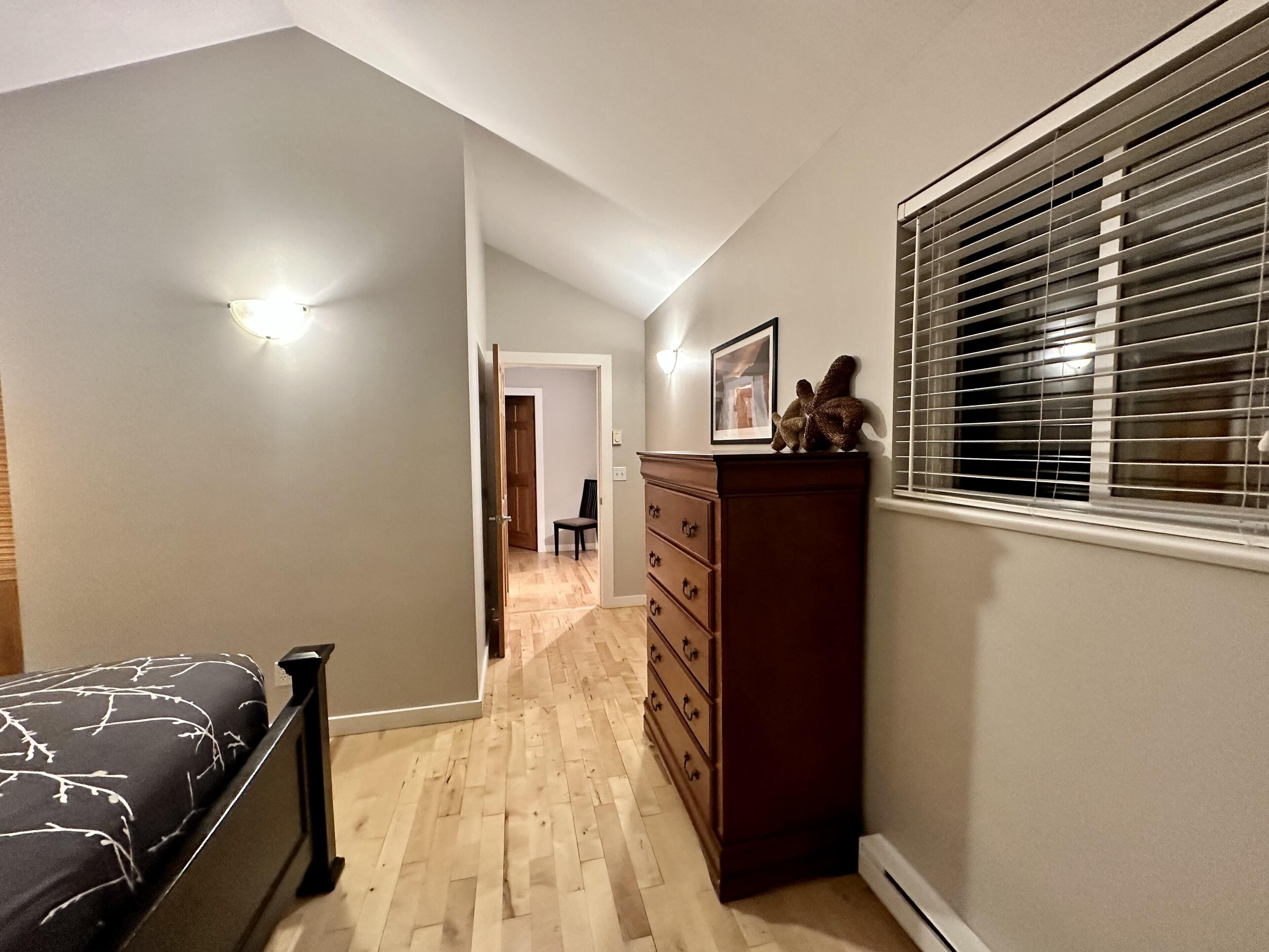 Un dormitorio con cama, cómoda y ventana con persianas.