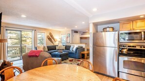 Una cocina moderna con electrodomésticos de acero inoxidable, un comedor con mesa y sillas de madera, y una sala de estar acogedora con un sofá modular.