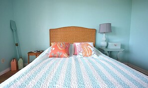 Ein Schlafzimmer mit einem Bett, zwei Kissen, einem Nachttisch, einer Lampe und einem an der Wand befestigten Regal.