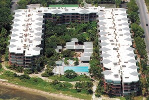Ein Hotel mit mehreren Gebäuden, einem zentral gelegenen Pool und umgebender Grünfläche.