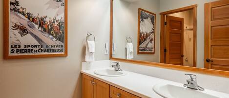 A bathroom with two sinks, wooden cabinets, and a large mirror.