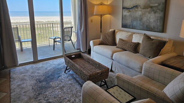 A living room with a sofa, a wicker basket, a lamp, and a painting. - Inn at Dauphin Island 411 Beautiful Unit with Incredible Views!! (Dauphin Island)
