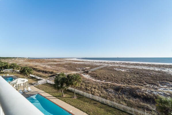A beachfront property with a swimming pool, lounge chairs, and a view of the beach and ocean. - Inn at Dauphin Island 411 Beautiful Unit with Incredible Views!! (Dauphin Island)