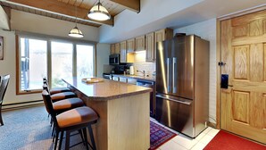 A modern kitchen with a central island, stainless steel appliances, and wooden cabinetry. - 🌲Timberline A2E Deluxe 2-Bedroom ~Hot Tub~Pool~WiFi~Ski-in/out~Local Shuttle🌲 (Snowmass Village)
