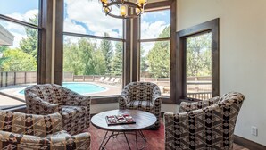 A room with large windows, a pool, and patterned furniture. - Snowcreek Condo 1516 - Room for up to 8 Guests & Sun Valley Resort Amenities (Sun Valley)