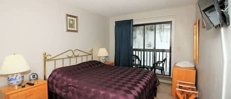 Habitación de hotel con cama, mesitas de noche, televisor, ventana con vistas y balcón.