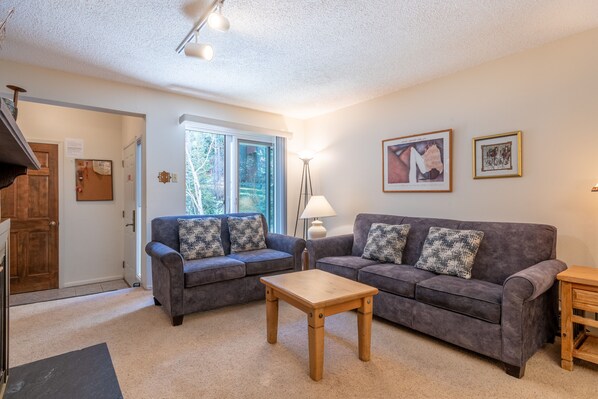 A living room with two grey sofas, a wooden coffee table, and a lamp. - Cozy Ski-in/Walk-out condo, free wifi, & parking, great value (Copper Mountain)