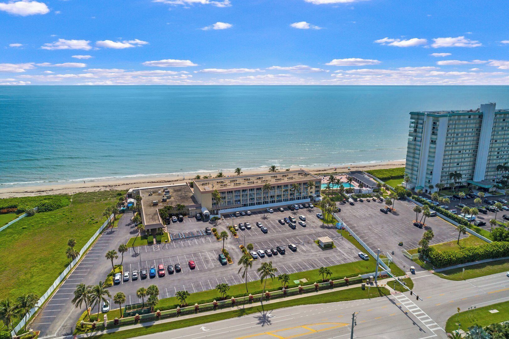Ein Hotel mit Parkplatz, Pool und Blick auf Strand und Meer.